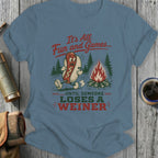 T-shirt graphic of a hot dog at a campfire with text, "It's All Fun and Games... Until Someone Loses a Weiner."