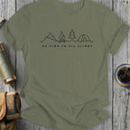 Olive green t-shirt with "BE KIND TO ALL CLIMBS" text and mountain, campfire, tree, and tent illustration.