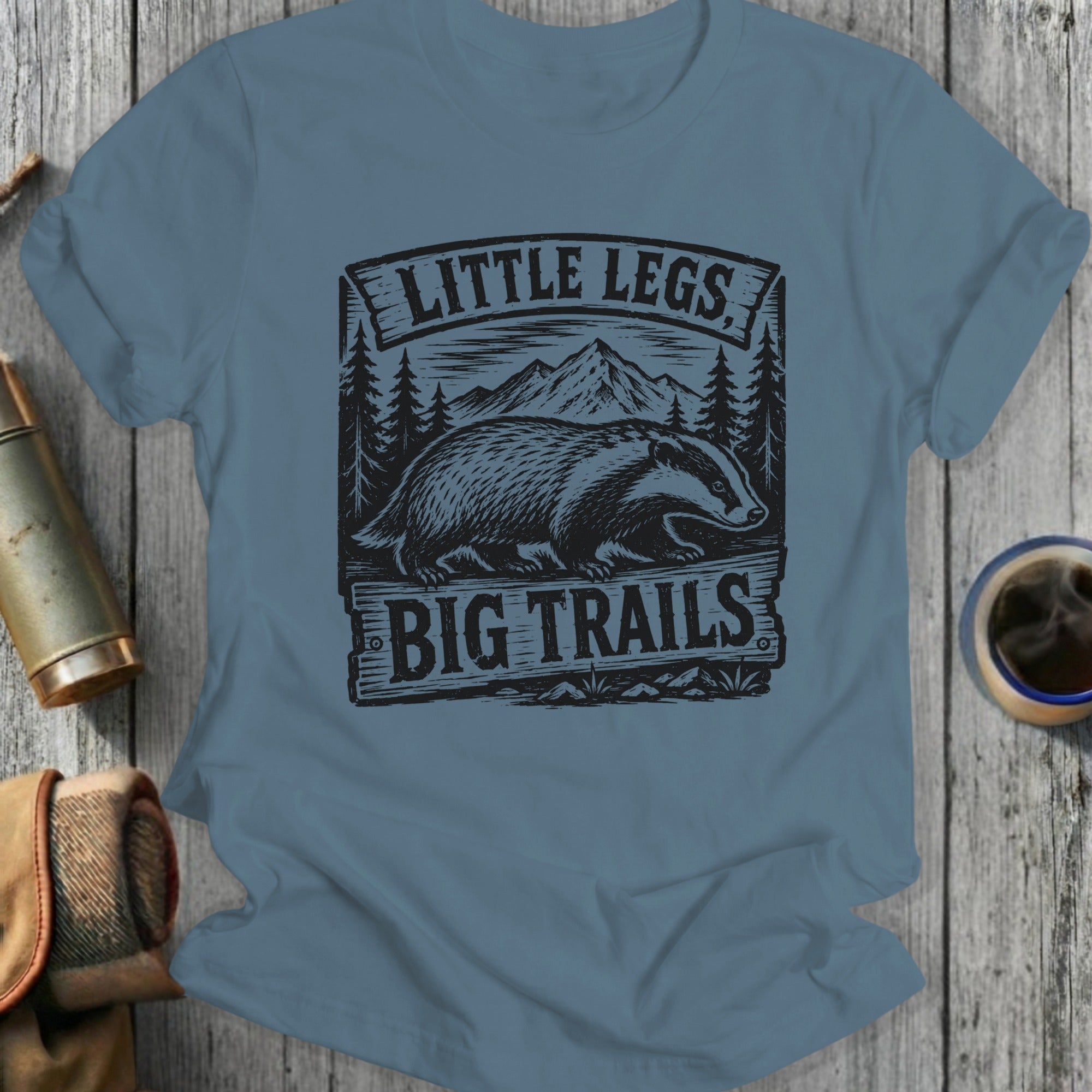 Badger illustration with text "LITTLE LEGS BIG TRAILS" on t-shirt.
