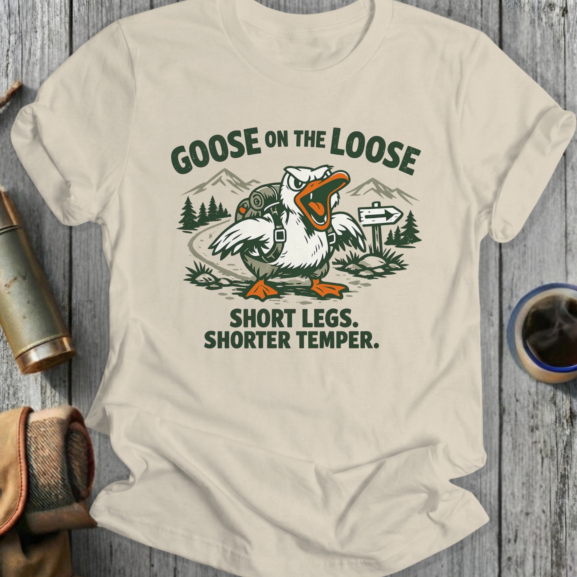T-shirt with cartoon goose hiking, reads "GOOSE ON THE LOOSE. SHORT LEGS. SHORTER TEMPER."
