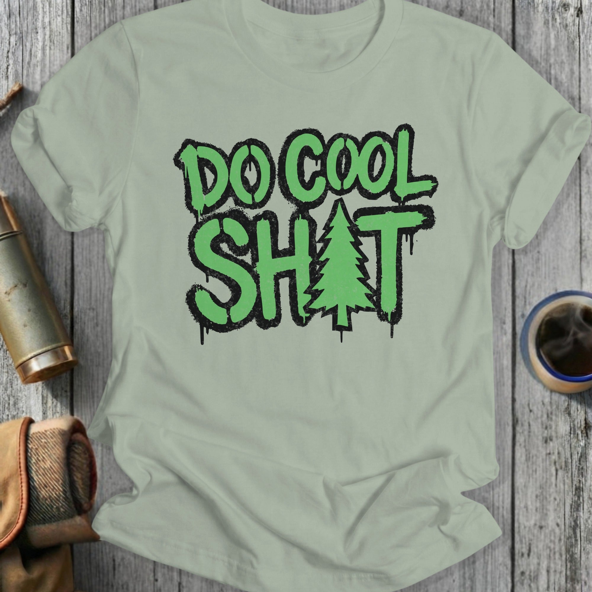 Green t-shirt with "DO COOL SH*T" text and a pine tree graphic.