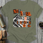 Olive green t-shirt with "Not Lost. Just Ignoring You." text and mountain graphic.
