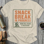 Light cream t-shirt with distressed graphic of a hiker and text "SNACK BREAK IN PROGRESS".