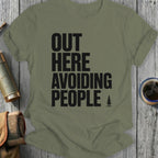 Olive green t-shirt with "OUT HERE AVOIDING PEOPLE" text and a small tree.