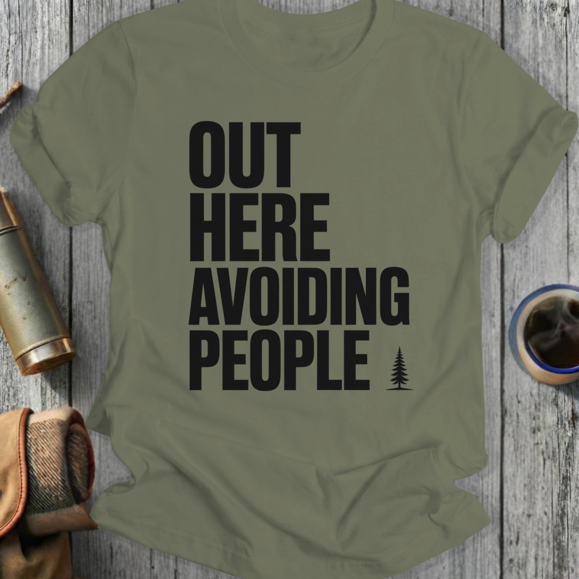 Olive green t-shirt with "OUT HERE AVOIDING PEOPLE" text and a small tree.