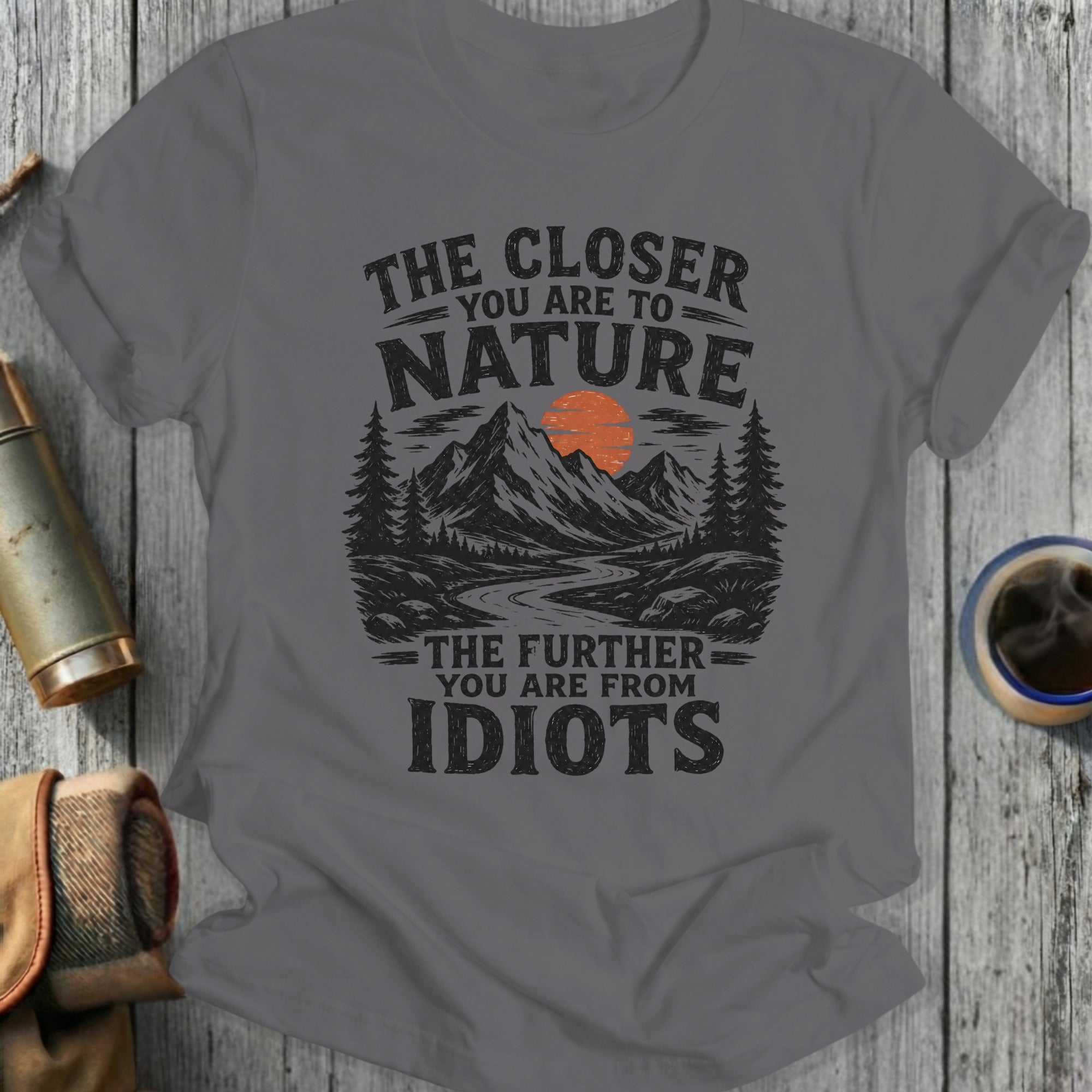 Gray t-shirt with "The Closer You Are To Nature, The Further You Are From Idiots" text and mountain graphic.