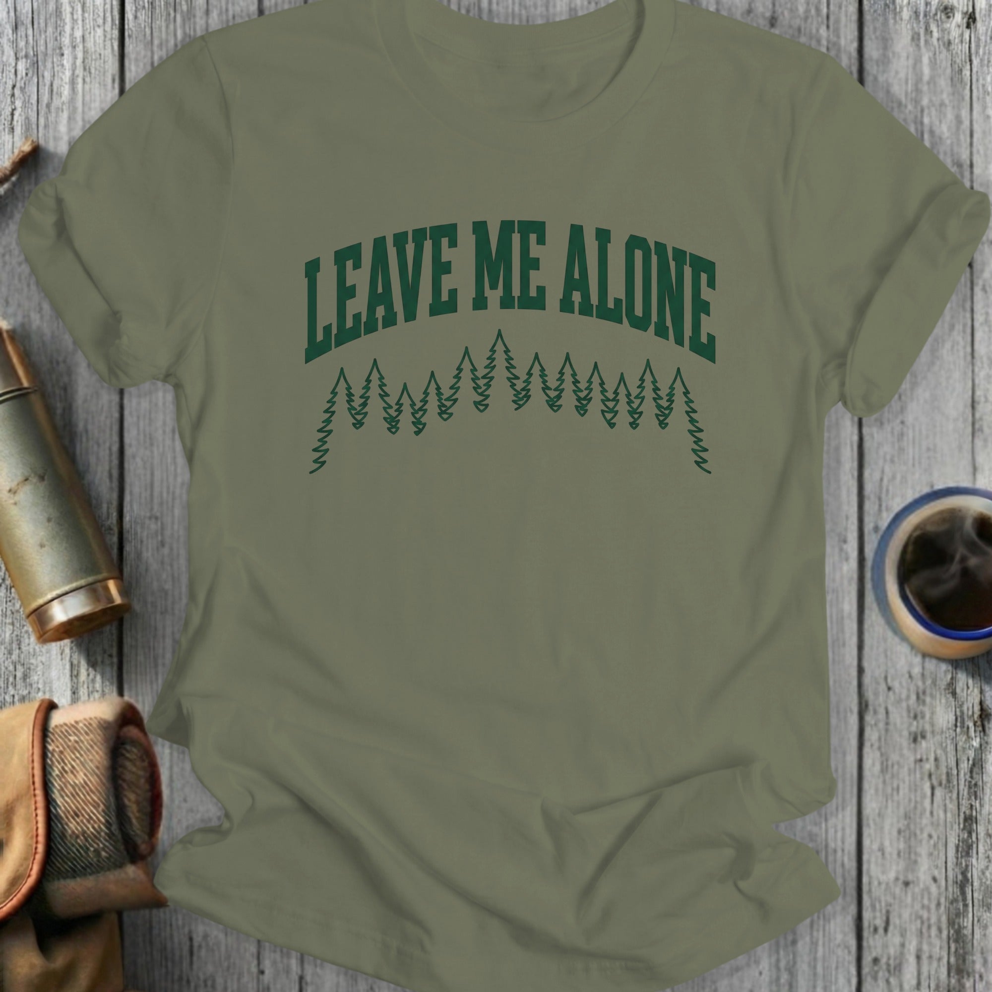 Olive green t-shirt with "LEAVE ME ALONE" text and pine tree graphic.