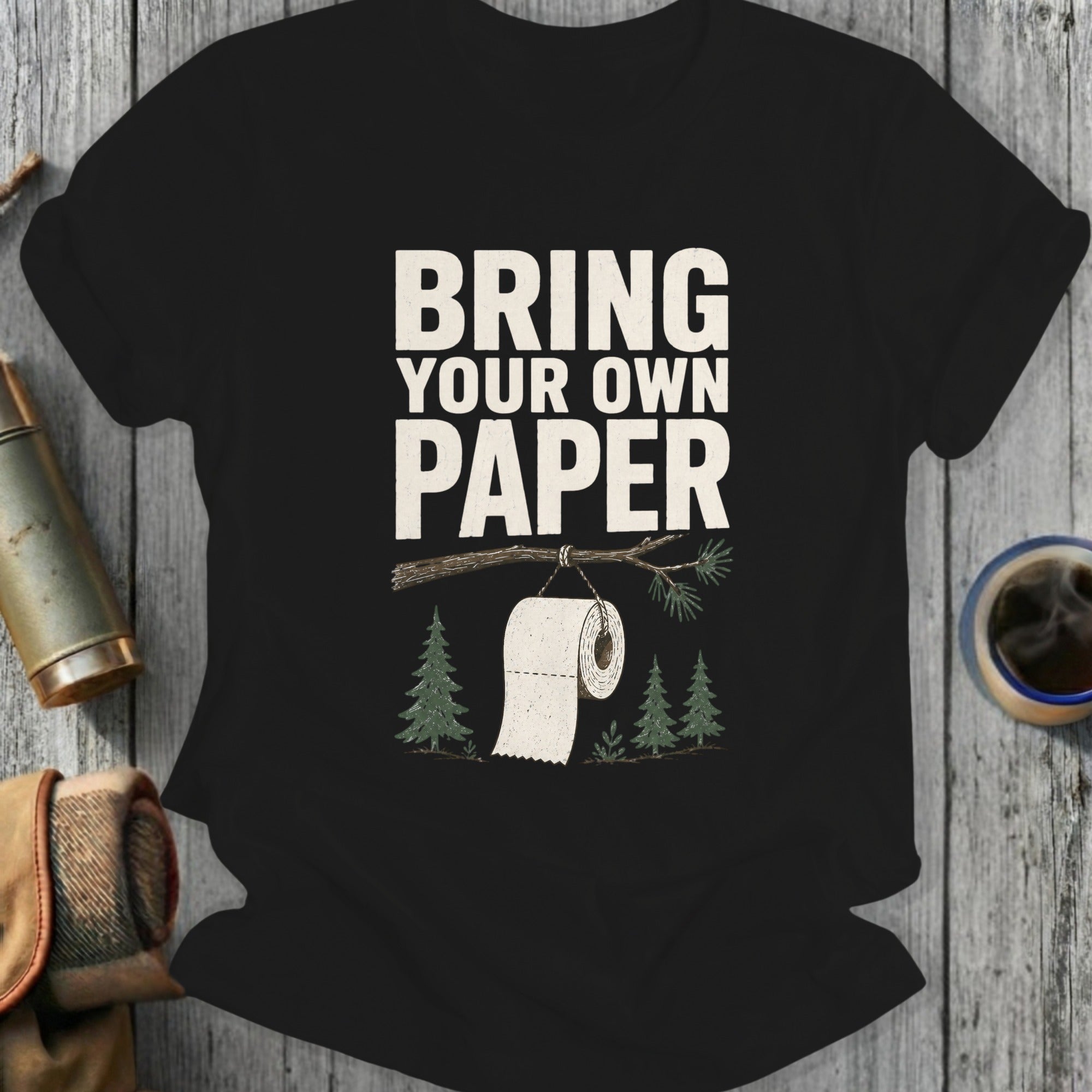 Black t-shirt with "Bring Your Own Paper" text, toilet paper on a branch, and trees.