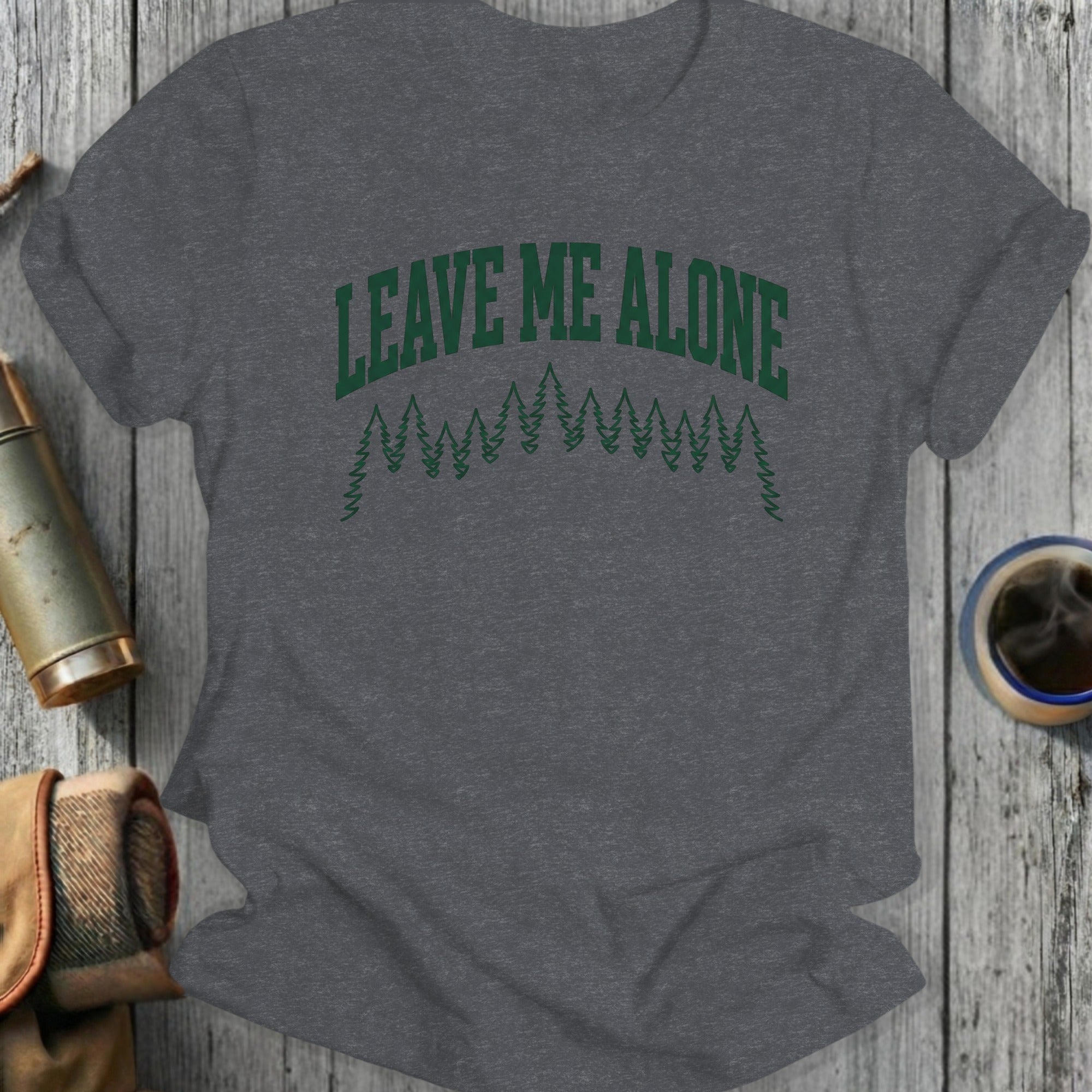 Dark grey t-shirt with "LEAVE ME ALONE" in green forest graphic.