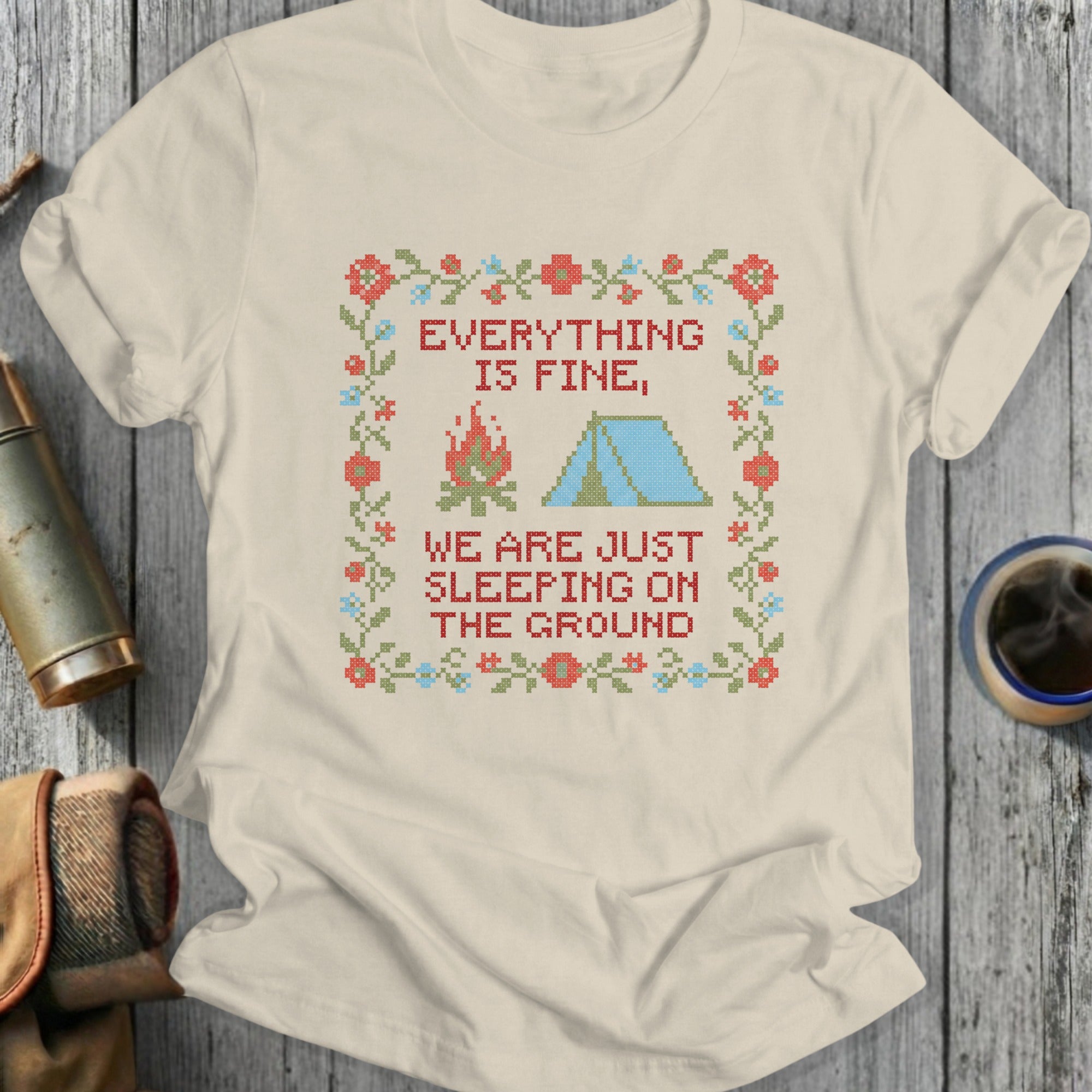 T-shirt with embroidered campsite and text "EVERYTHING IS FINE, WE ARE JUST SLEEPING ON THE GROUND".