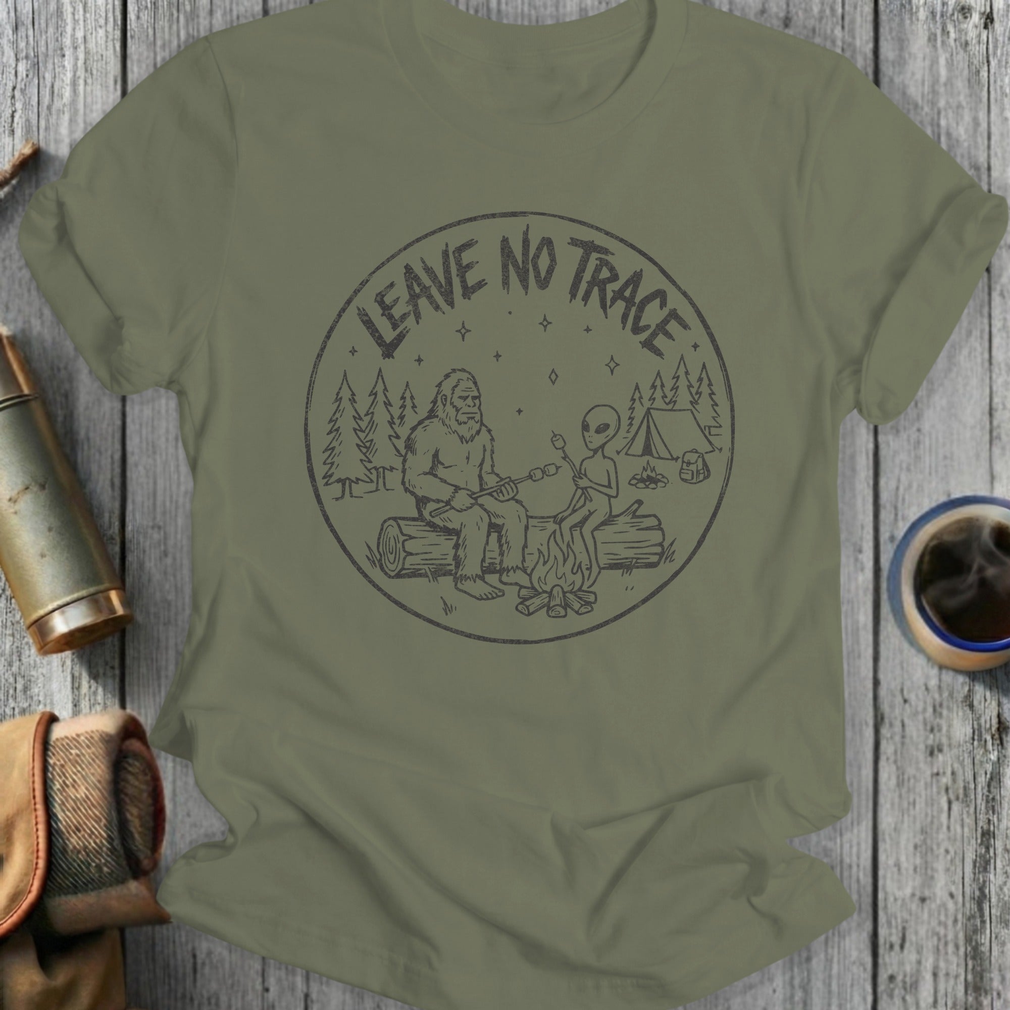 Bigfoot and alien roast marshmallows by campfire, with "Leave No Trace" text.
