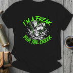Black t-shirt with green "I'm a freak for the creek" graphic featuring Bigfoot's foot splashing water.