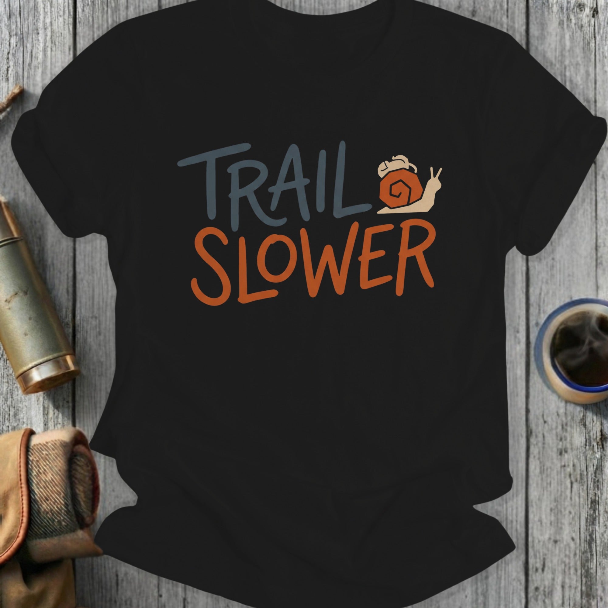 Black t-shirt with "TRAIL SLOWER" text and a snail graphic.