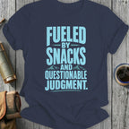T-shirt with light blue text: "FUELED BY SNACKS AND QUESTIONABLE JUDGMENT."