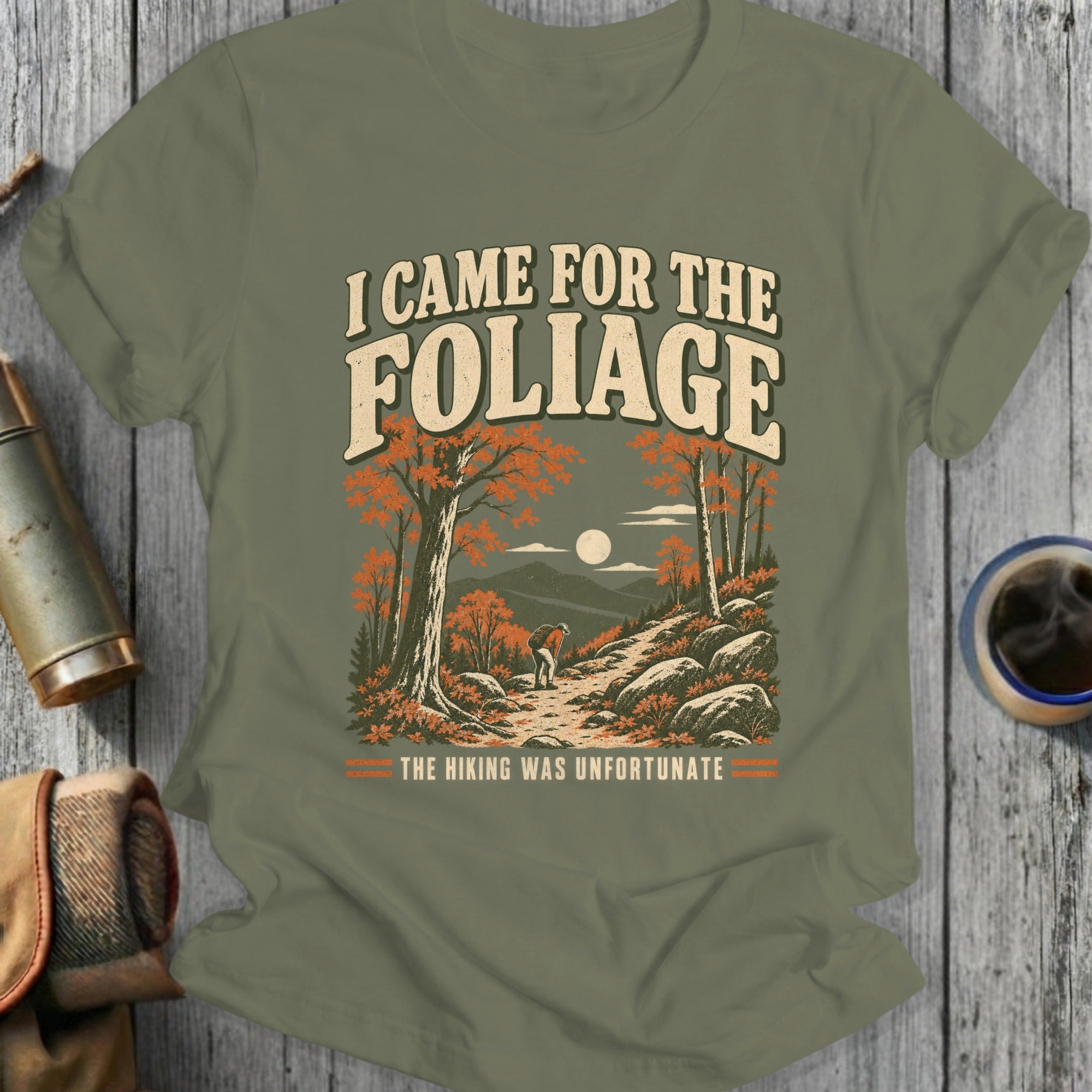 T-shirt with "I Came For The Foliage" and "The Hiking Was Unfortunate" text and mountain scene.
