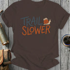 Brown t-shirt with "TRAIL SLOWER" text and a snail graphic.