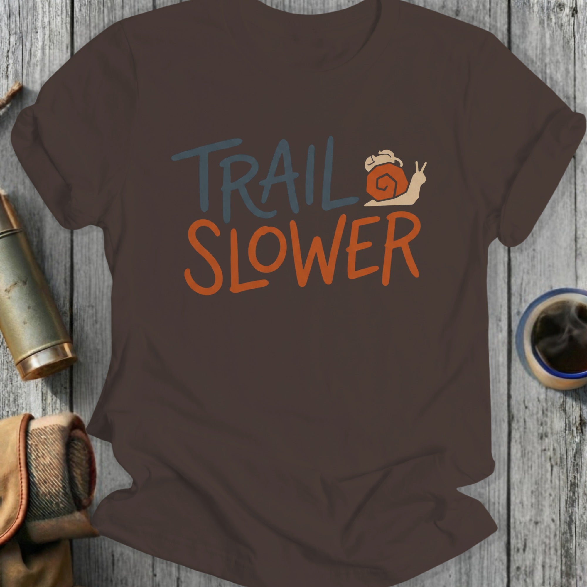 Brown t-shirt with "TRAIL SLOWER" text and a snail graphic.