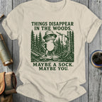Frog in bucket hat standing in woods with text "Things disappear in the woods. Maybe a sock. Maybe you."