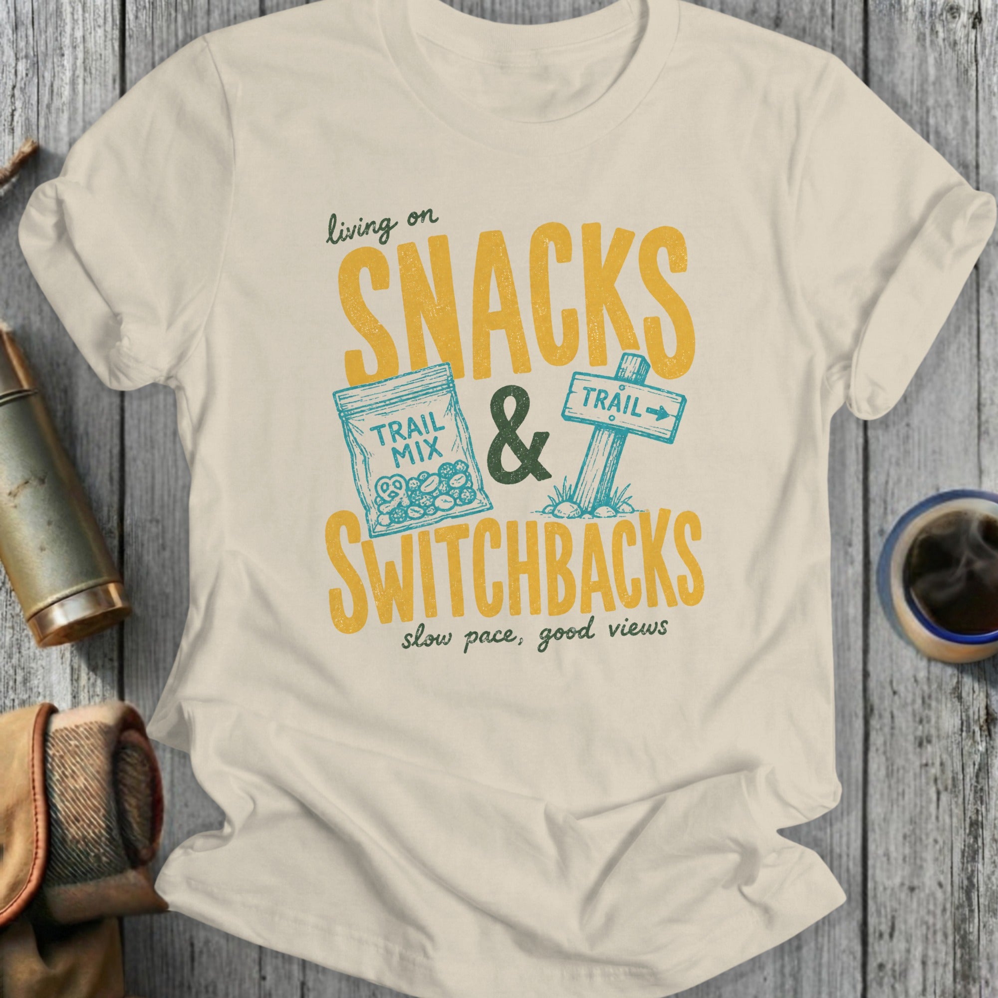 T-shirt with yellow text: "living on SNACKS & SWITCHBACKS slow pace, good views"