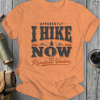Orange t-shirt with "Apparently I Hike Now Recreational Wanderer" graphic.