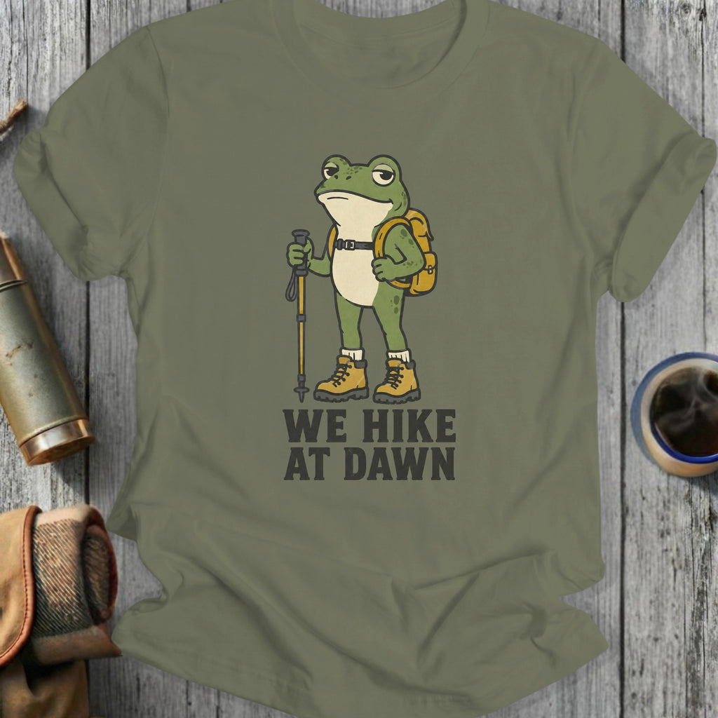 Green t-shirt with cartoon frog hiker and text "WE HIKE AT DAWN".