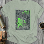 Green Bigfoot and alien figures on a distressed background with "LEAVE NO TRACE" text.