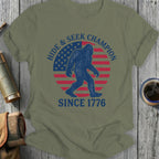 Bigfoot silhouette over US flag with "Hide & Seek Champion Since 1776" text.