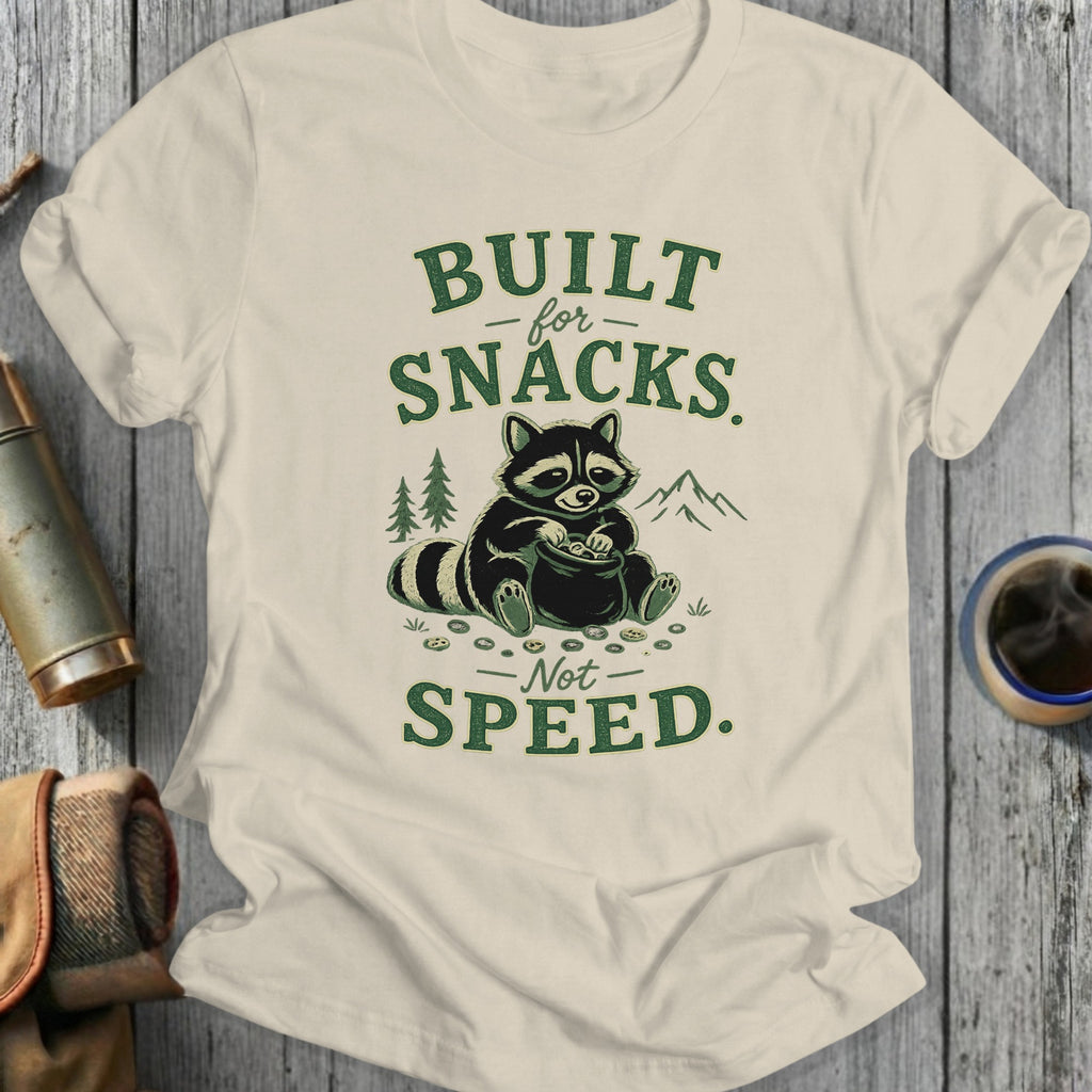 T-shirt with raccoon collecting snacks, text reads "BUILT for SNACKS - Not SPEED."