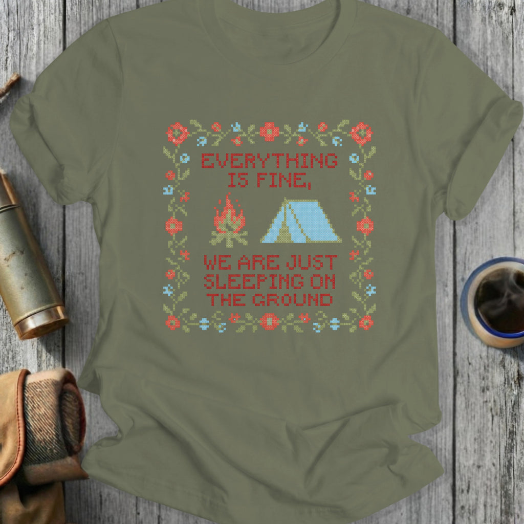 Green t-shirt with "Everything is fine, we are just sleeping on the ground" text and camping graphic.
