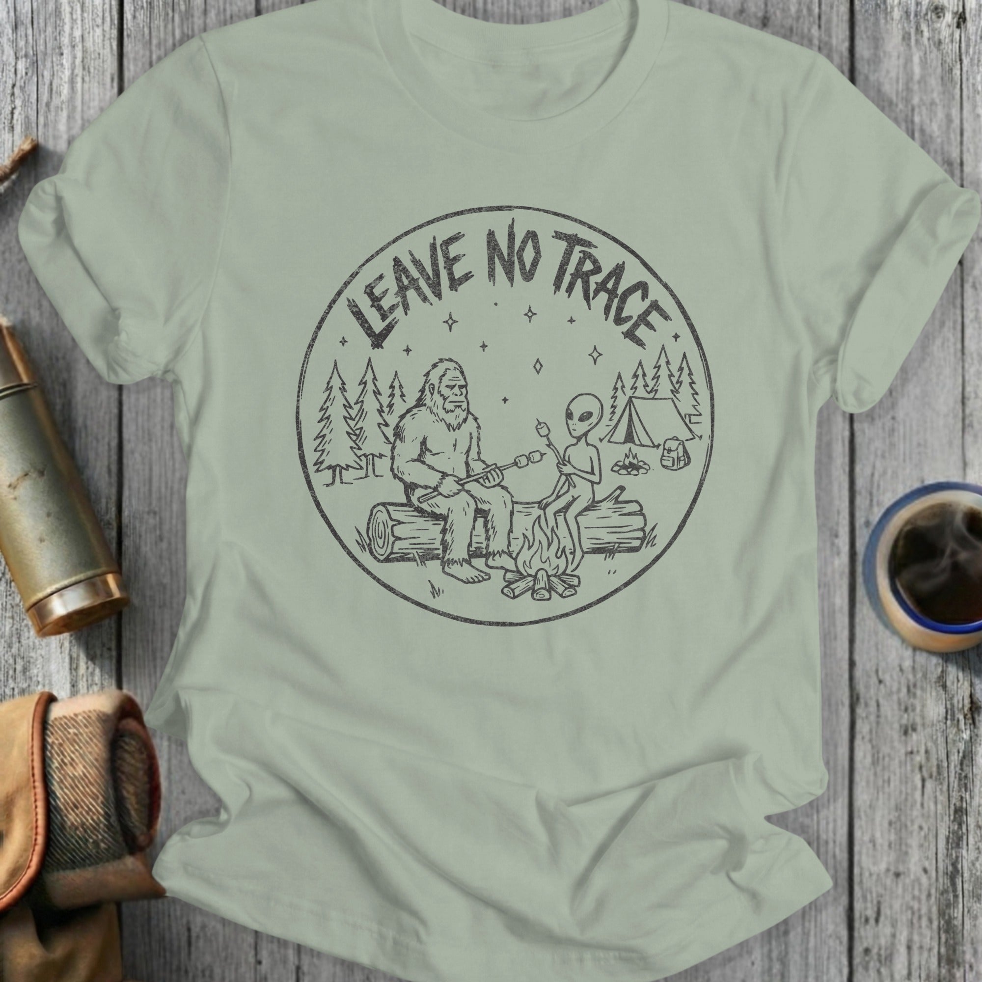 T-shirt graphic with Bigfoot and alien sitting by campfire, "Leave No Trace" text.