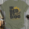 Olive green t-shirt with distressed text reading "IN BED BY 9:00 The Great Indoorsy Tour".