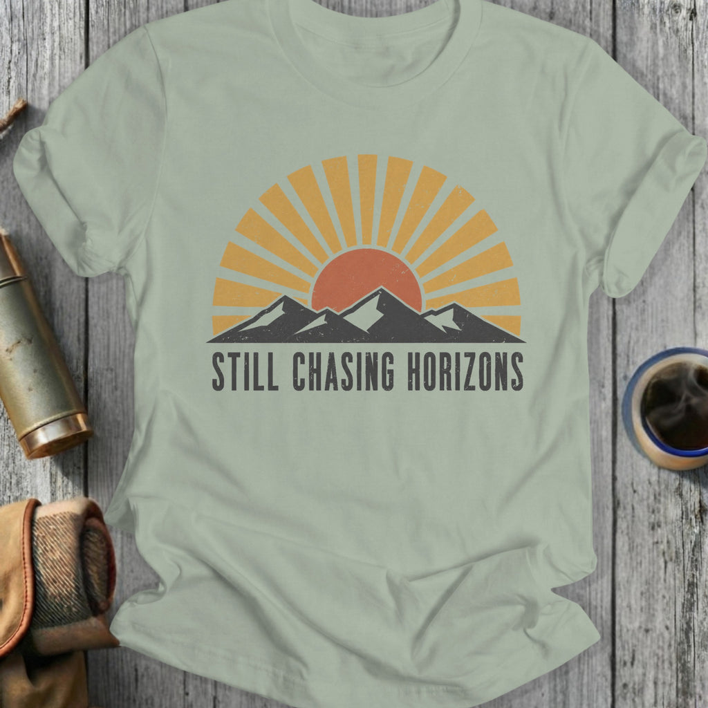 Light green t-shirt with sun, mountains, and "Still Chasing Horizons" text.