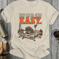 Skeleton hiker with backpack lies on ground with text "THE TRAIL SAID EASY".