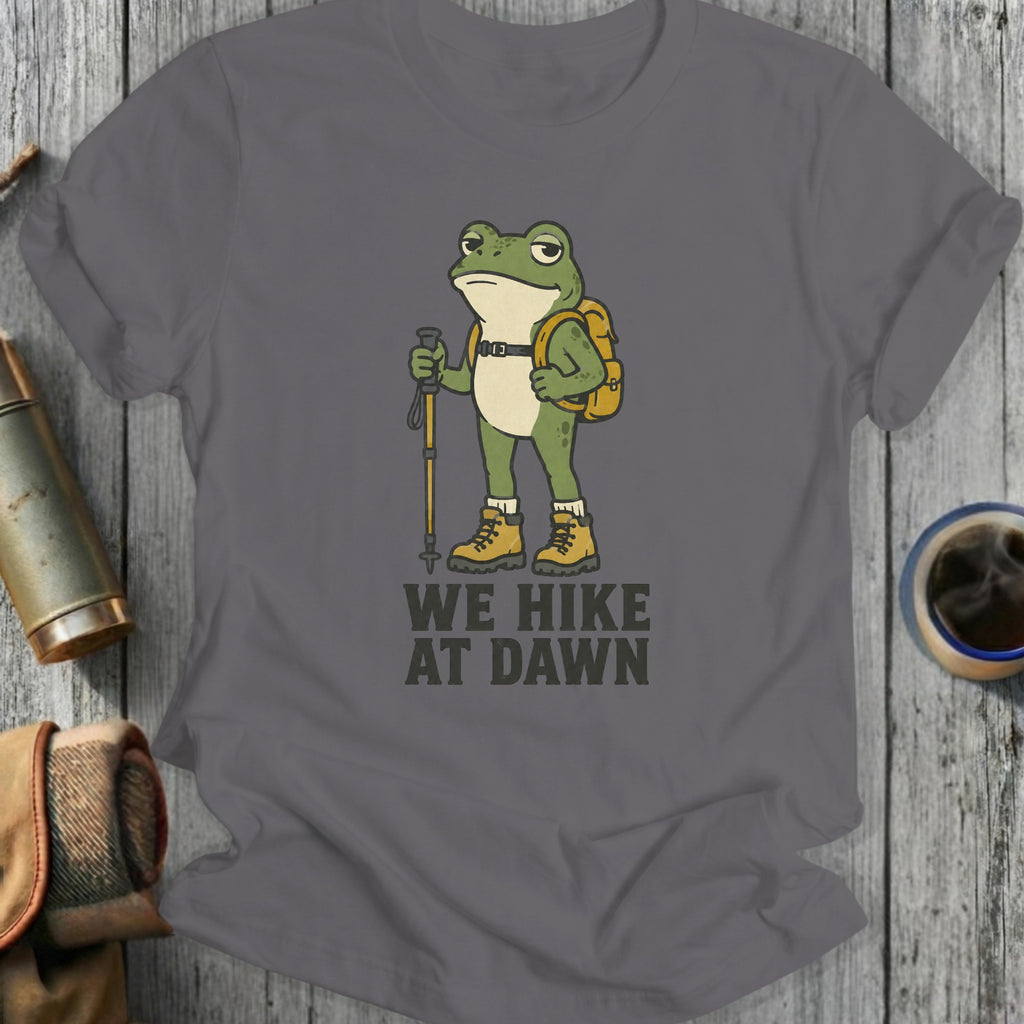 T-shirt with cartoon frog wearing backpack and holding hiking pole, text reads "WE HIKE AT DAWN"