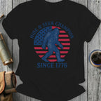 Bigfoot silhouette on American flag circle, "Hide & Seek Champion Since 1776."