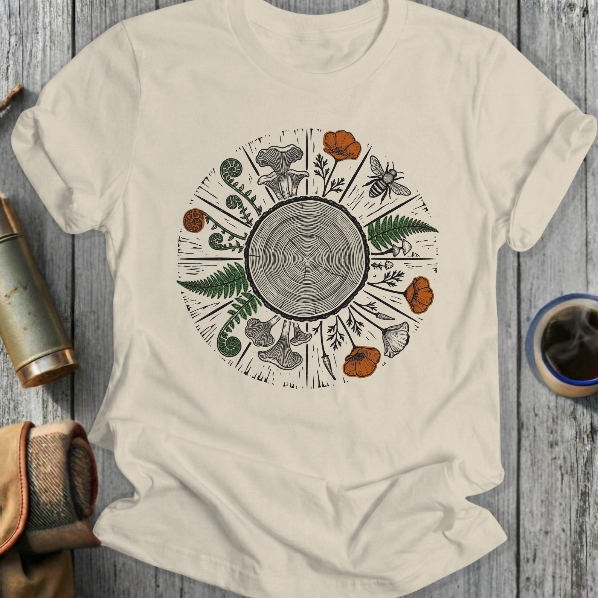 T-shirt with wood grain circle, ferns, mushrooms, poppies, and a bee.
