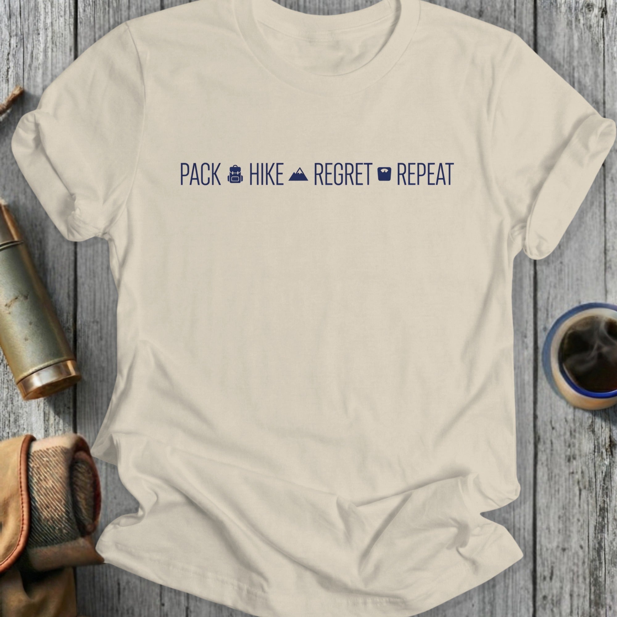 Light beige t-shirt with "PACK HIKE REGRET REPEAT" text and icons.