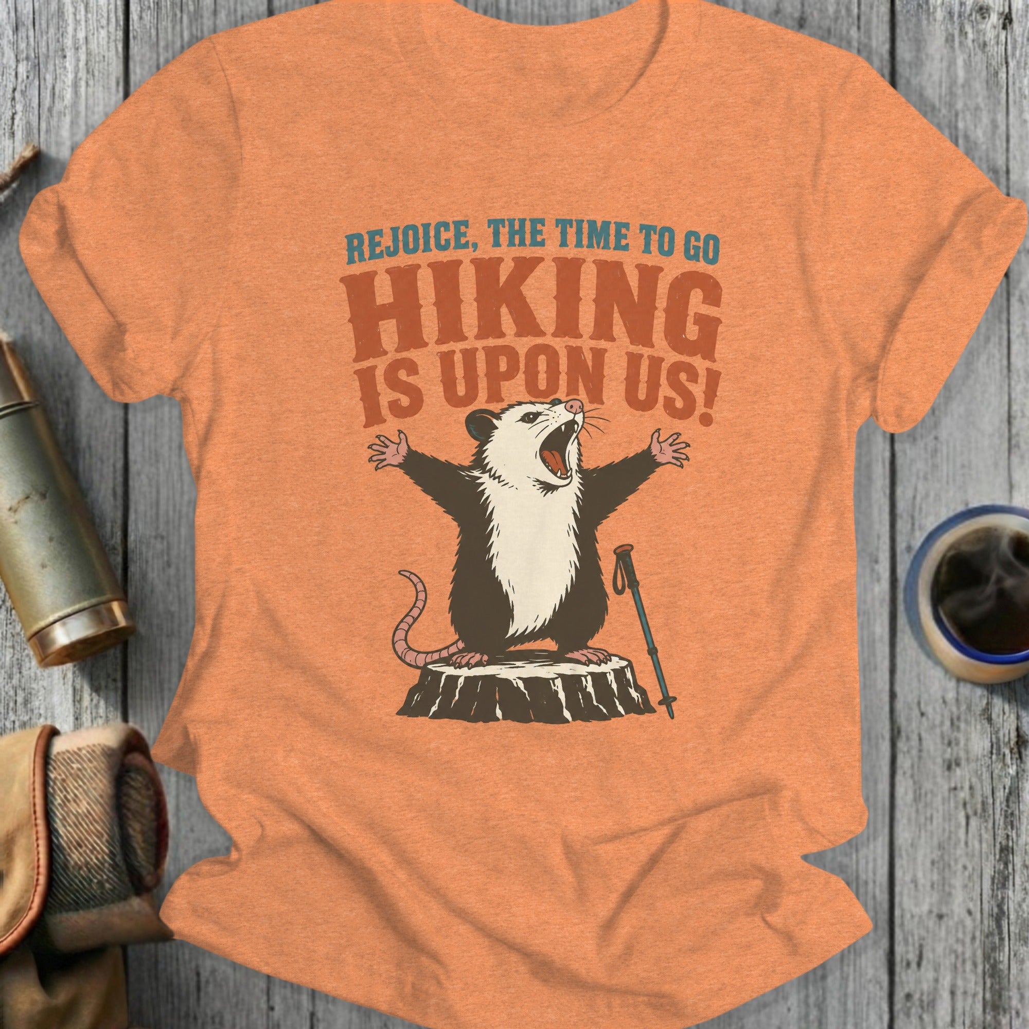 Opossum on a tree stump with arms outstretched, holding a hiking pole.