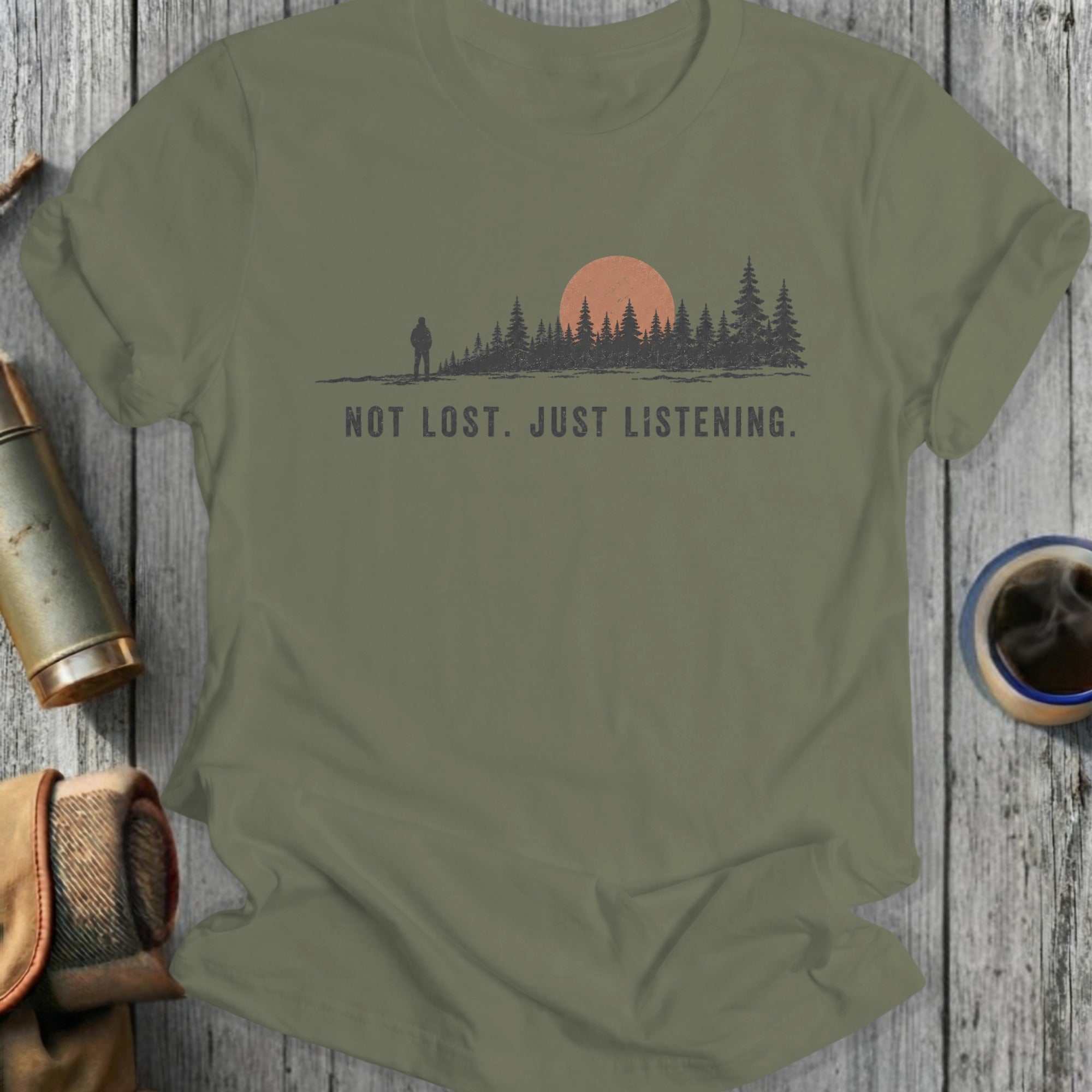 Olive green t-shirt with a forest silhouette, sun, and hiker graphic with text.