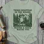 Frog in hat stands in woods with text: Things disappear in the woods. Maybe a sock. Maybe you.