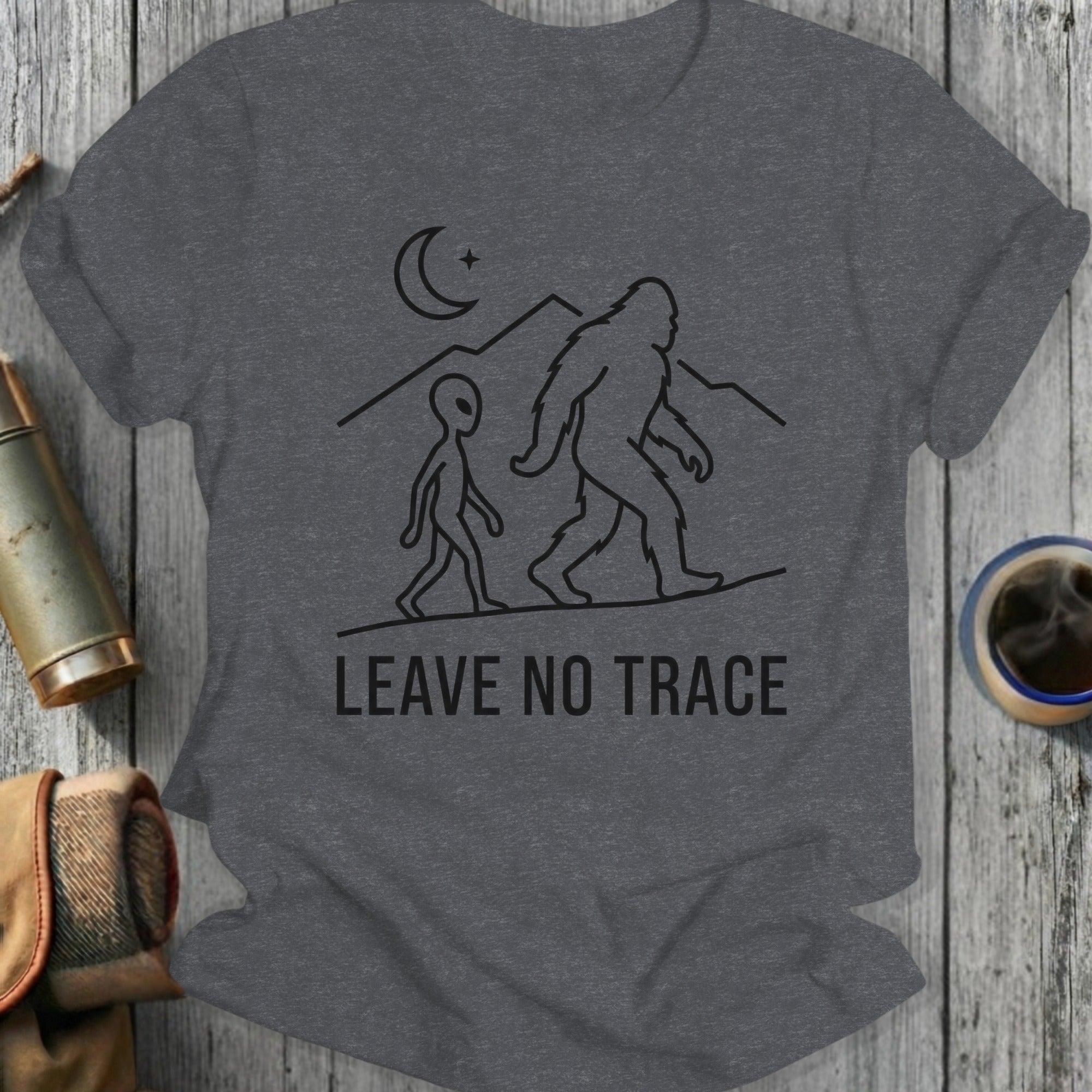 Graphic t-shirt with Bigfoot and alien silhouettes, moon, mountains, and "LEAVE NO TRACE" text.