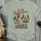 T-shirt with a hot dog character by a campfire, "It's All Fun and Games...Until Someone Loses a Weiner" text.