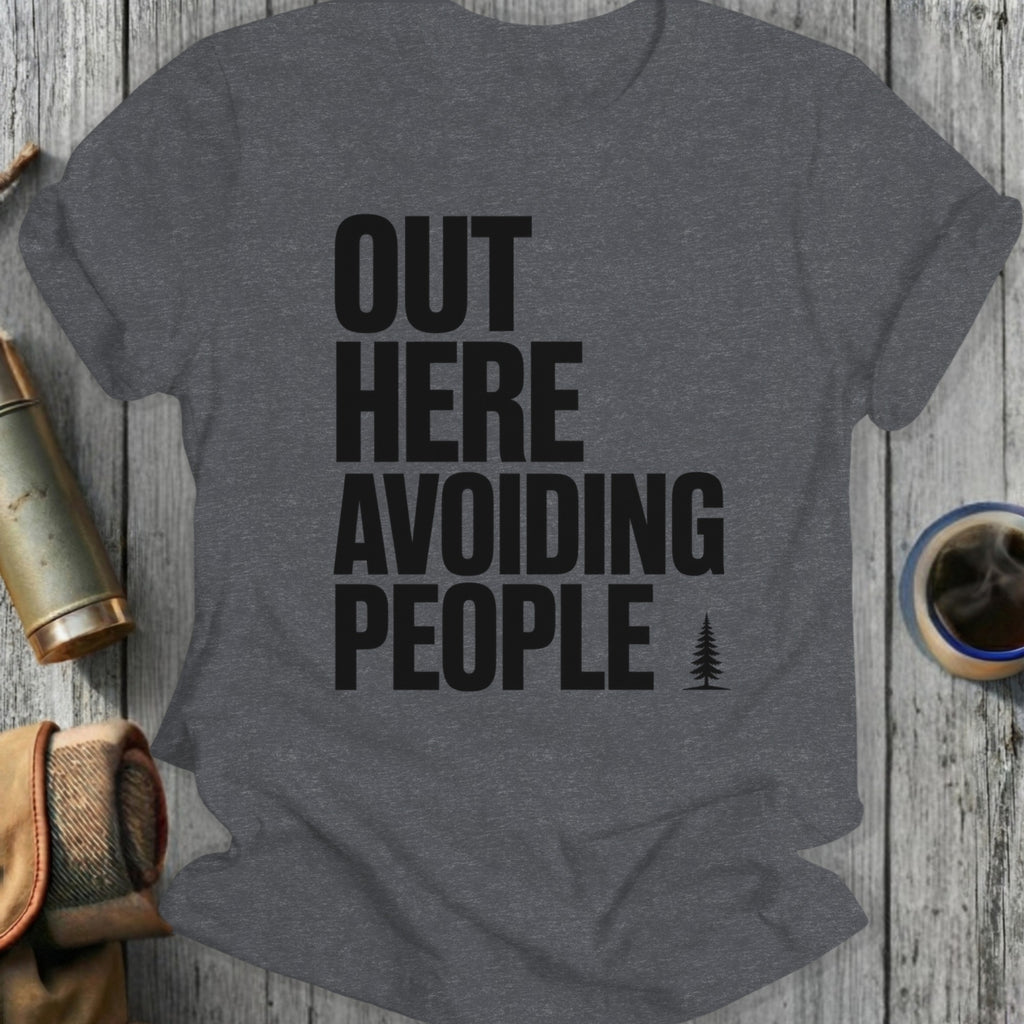 Dark gray t-shirt with "OUT HERE AVOIDING PEOPLE" text and a small tree icon.