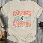 Cream t-shirt with text "raised on CAMPFIRES & CASSETTES good times, bad directions".
