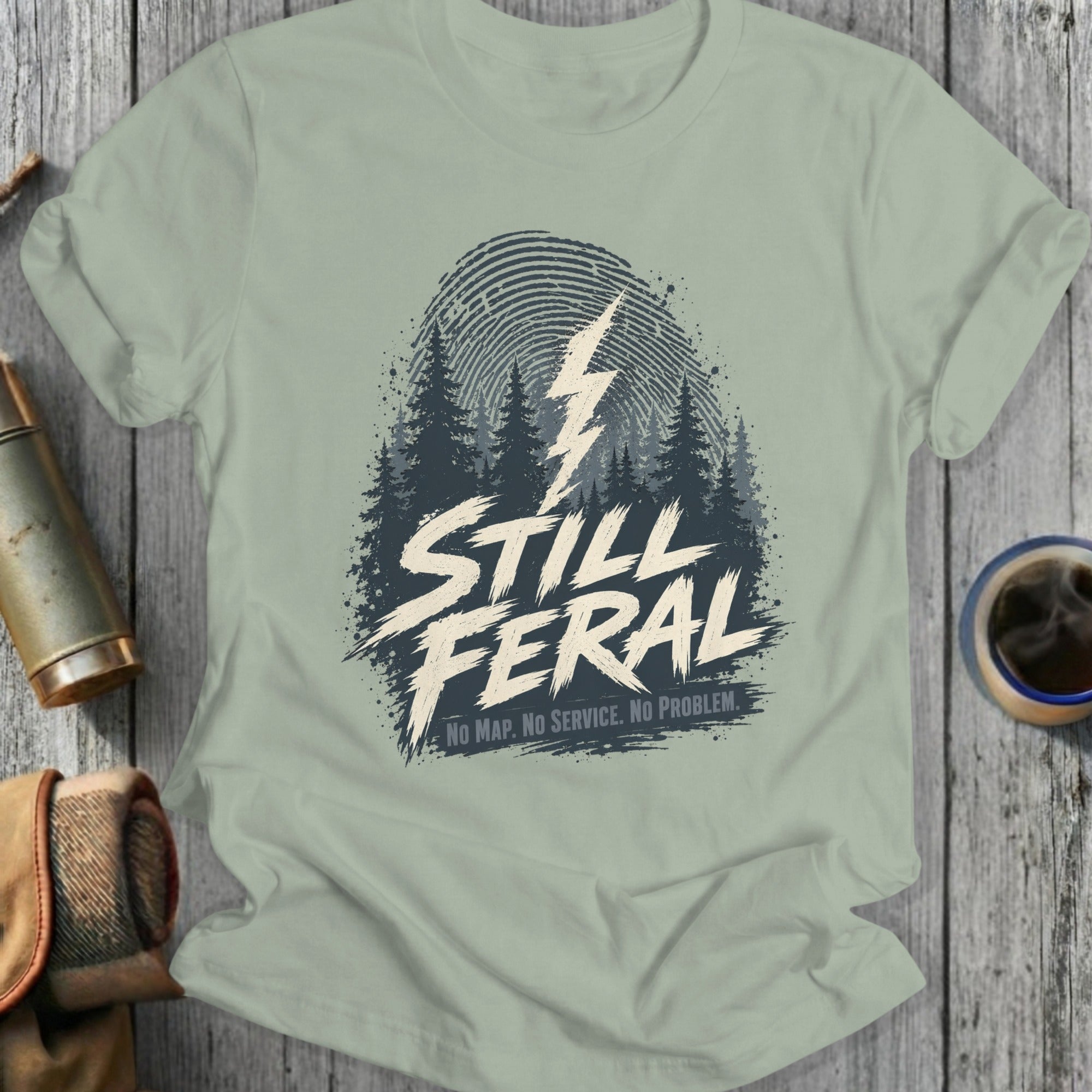 Light gray t-shirt with "Still Feral" and forest graphic.