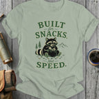 T-shirt with raccoon eating snacks, text "Built for Snacks. Not Speed."