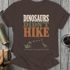 Brown t-shirt with "Dinosaurs Didn't Hike" text, footprints, and dinosaur graphic.